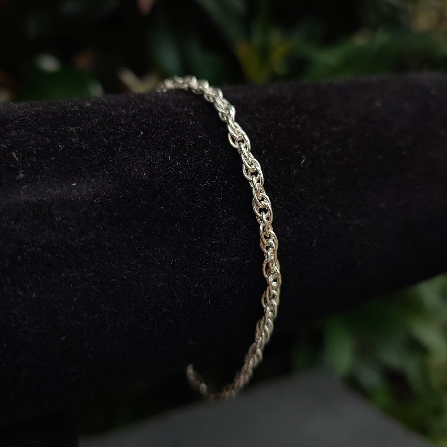 The silverhollowjewellery Rope Chain Bracelet Sterling Silver is showcased on a black velvet stand with a blurred green background, highlighting its classic rope link design.