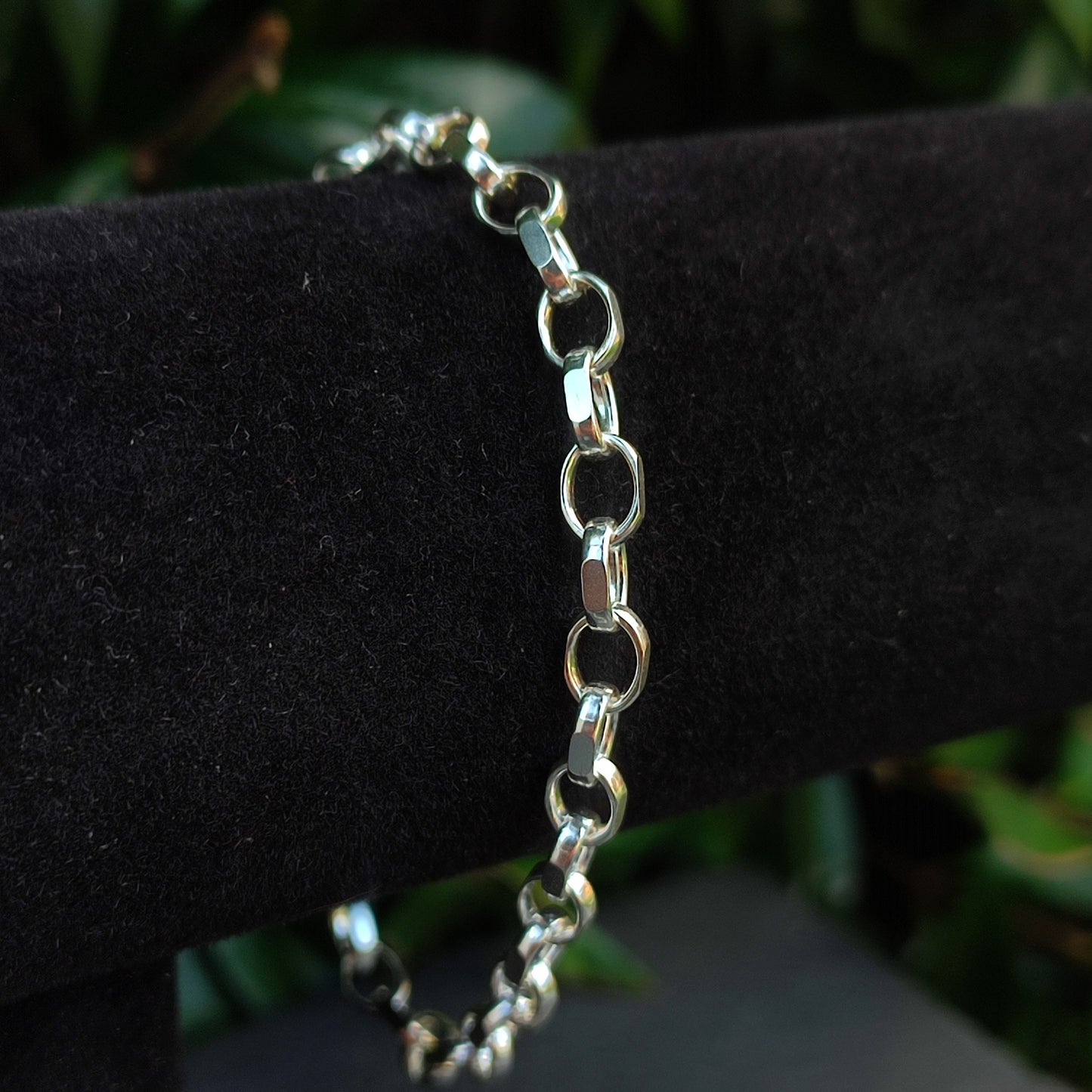 The silverhollowjewellery Belcher Chain Bracelet in sterling silver is shown on a black velvet stand, with blurred green foliage in the background.