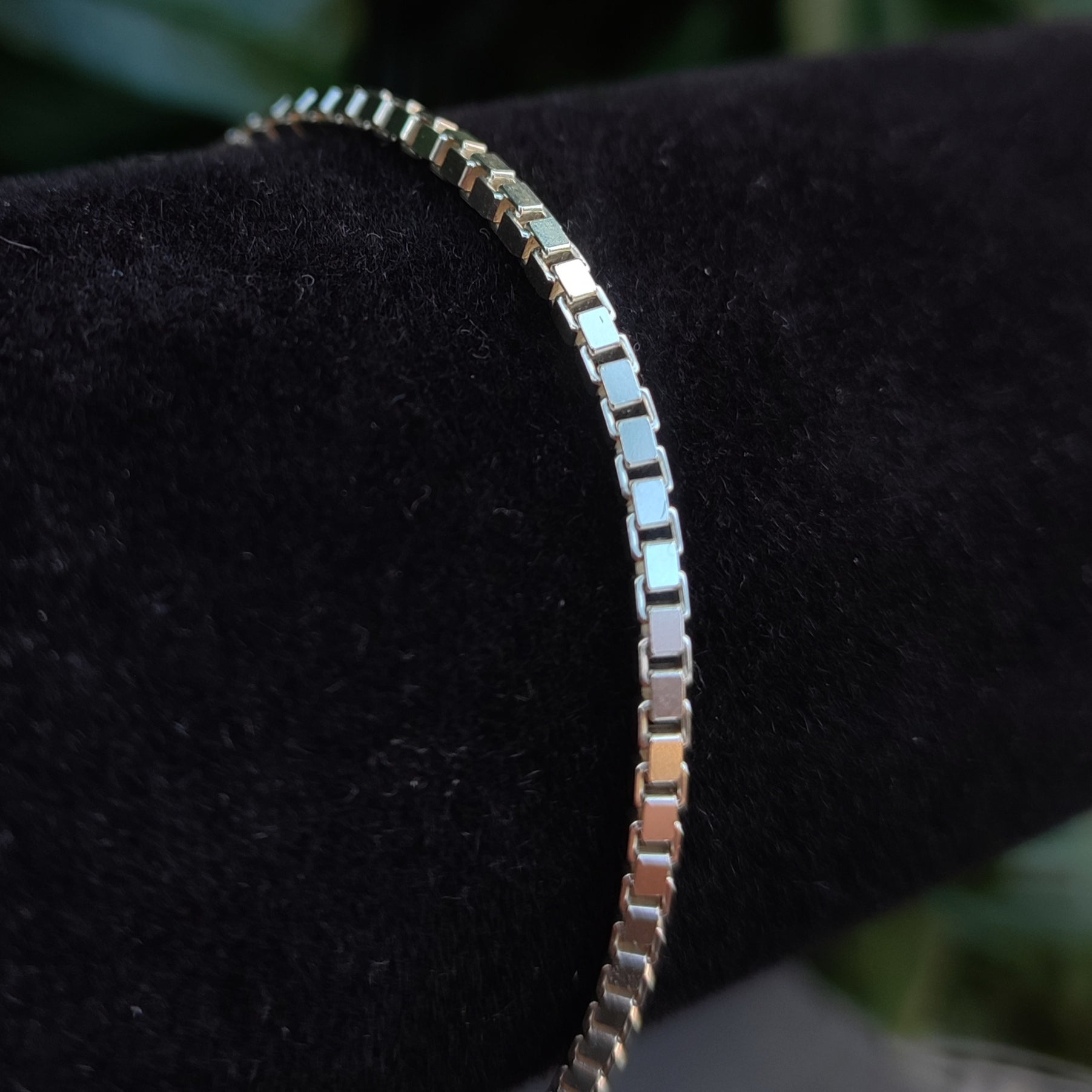 A close-up of the Box Chain Bracelet- Sterling Silver by silverhollowjewellery, showcased on a black velvet cylindrical stand.