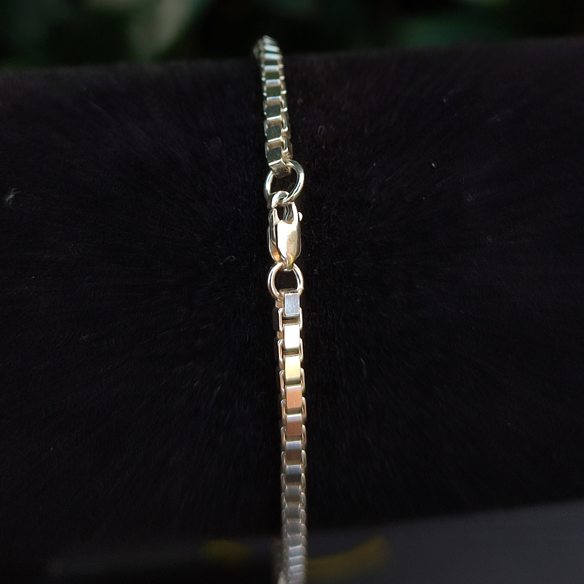A close-up of the silverhollowjewellery Box Chain Bracelet- Sterling Silver, featuring a lobster clasp, displayed on a black velvet background.