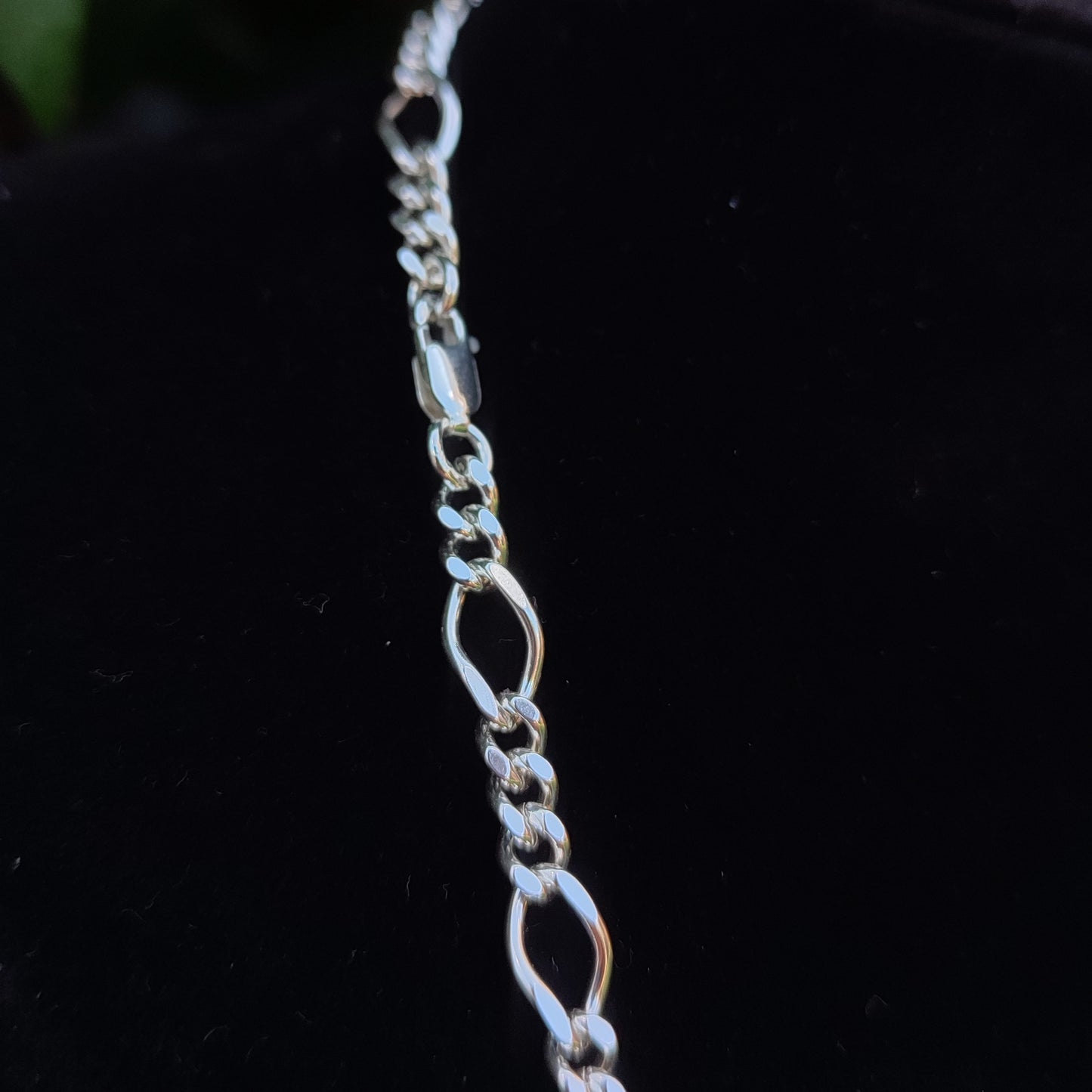 A close-up of the silverhollowjewellery Figaro Chain Necklace in sterling silver, featuring elegant links, displayed against a black background.