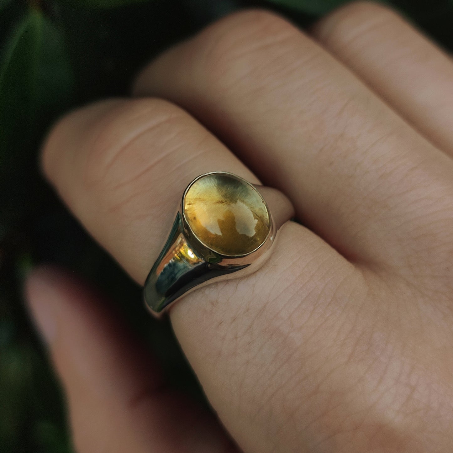 A hand wearing silverhollowjewellery's Gold Bezel Citrine Ring, featuring a large oval yellow citrine gemstone.