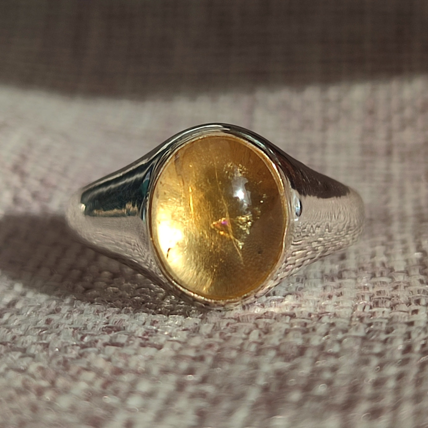 The Gold Bezel Citrine Ring by silverhollowjewellery is shown on a textured, light-colored fabric surface.
