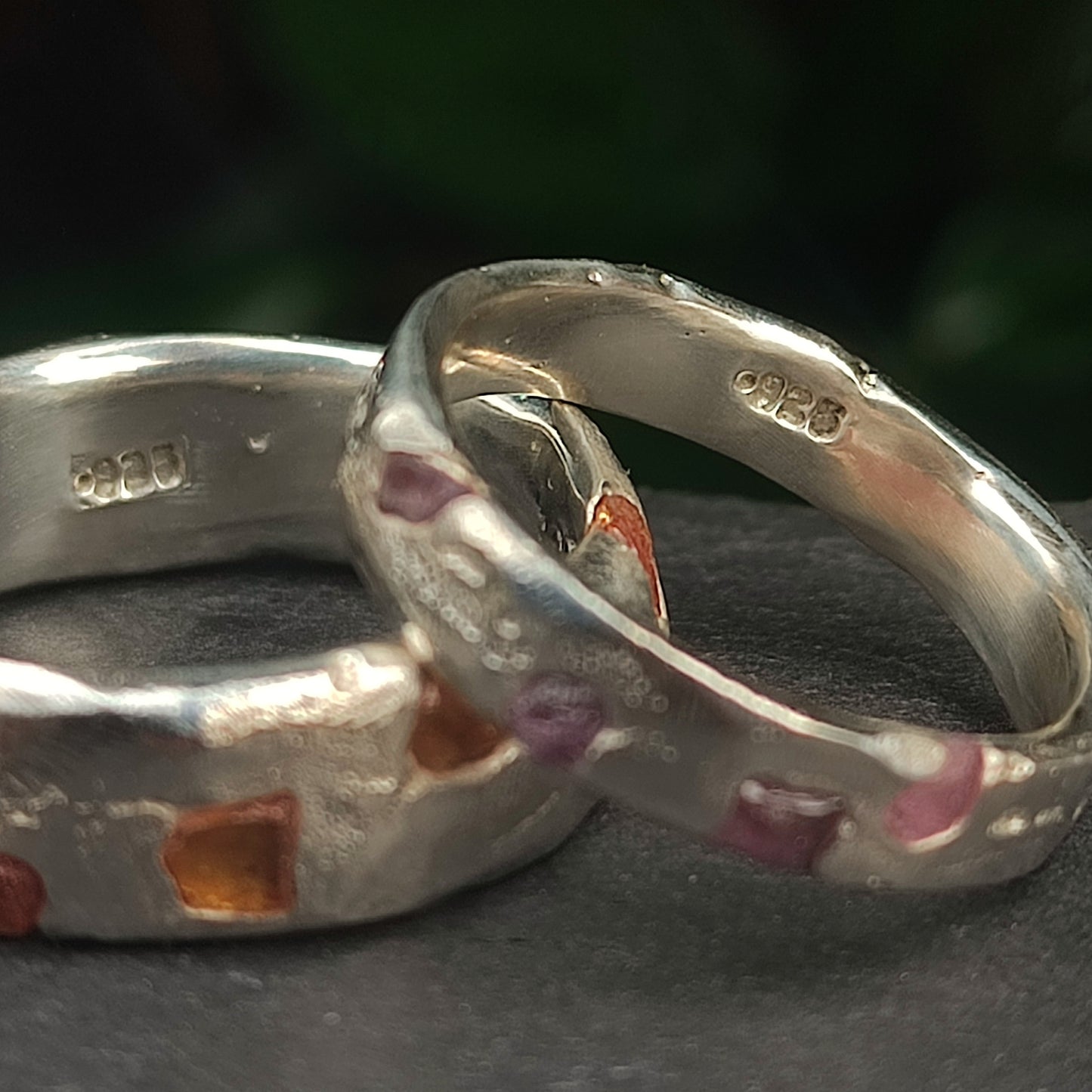 Two organic sterling silver rings by silverhollowjewellery; one is a custom Raw Sapphire Band with visible hallmarks and raw sapphires set in a textured, recycled band.