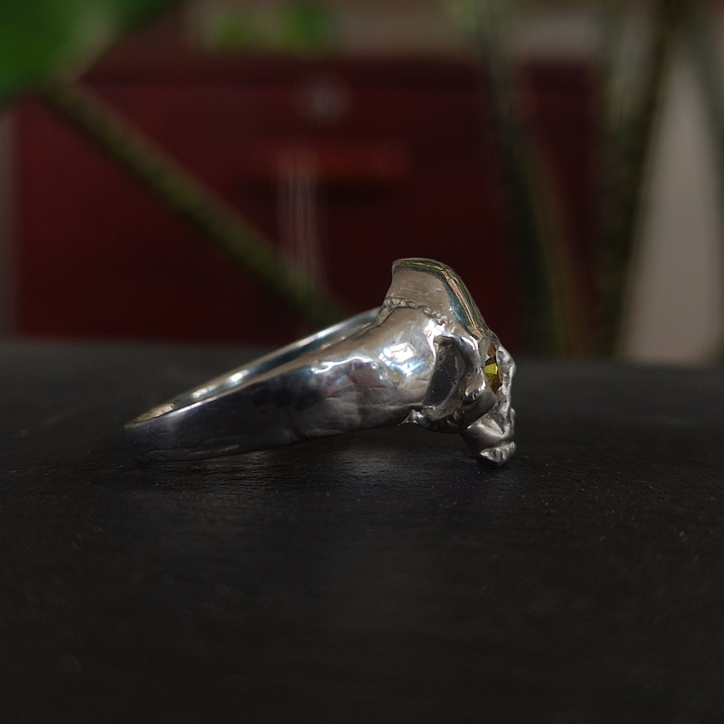 The yellow sapphire skull ring by silverhollowjewellery features a sculpted animal skull design in recycled sterling silver with detailed facial structure, showcased on a dark surface with a blurred background.