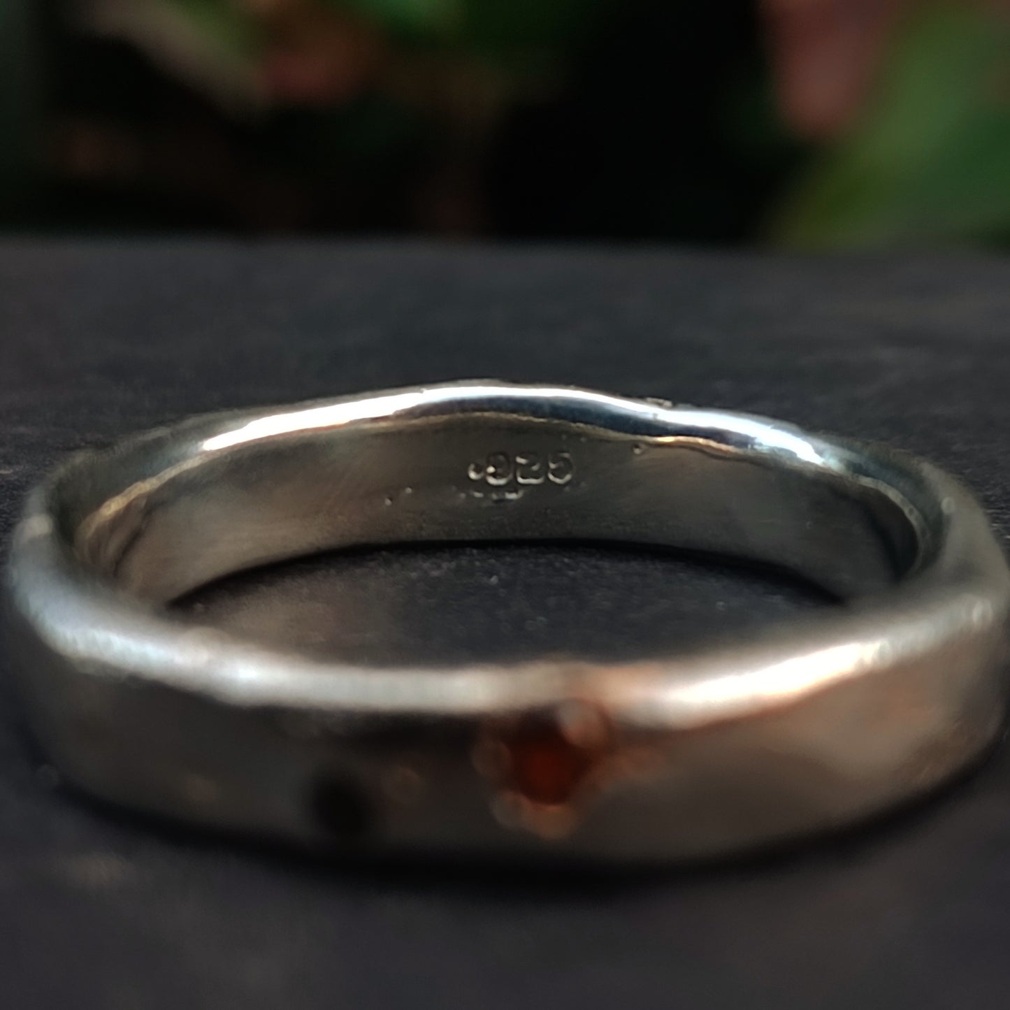 Close-up of the Sand Cast Sapphire Ring by silverhollowjewellery, crafted from recycled sterling silver and featuring a "925" stamp, displayed on a dark surface with a blurred background.