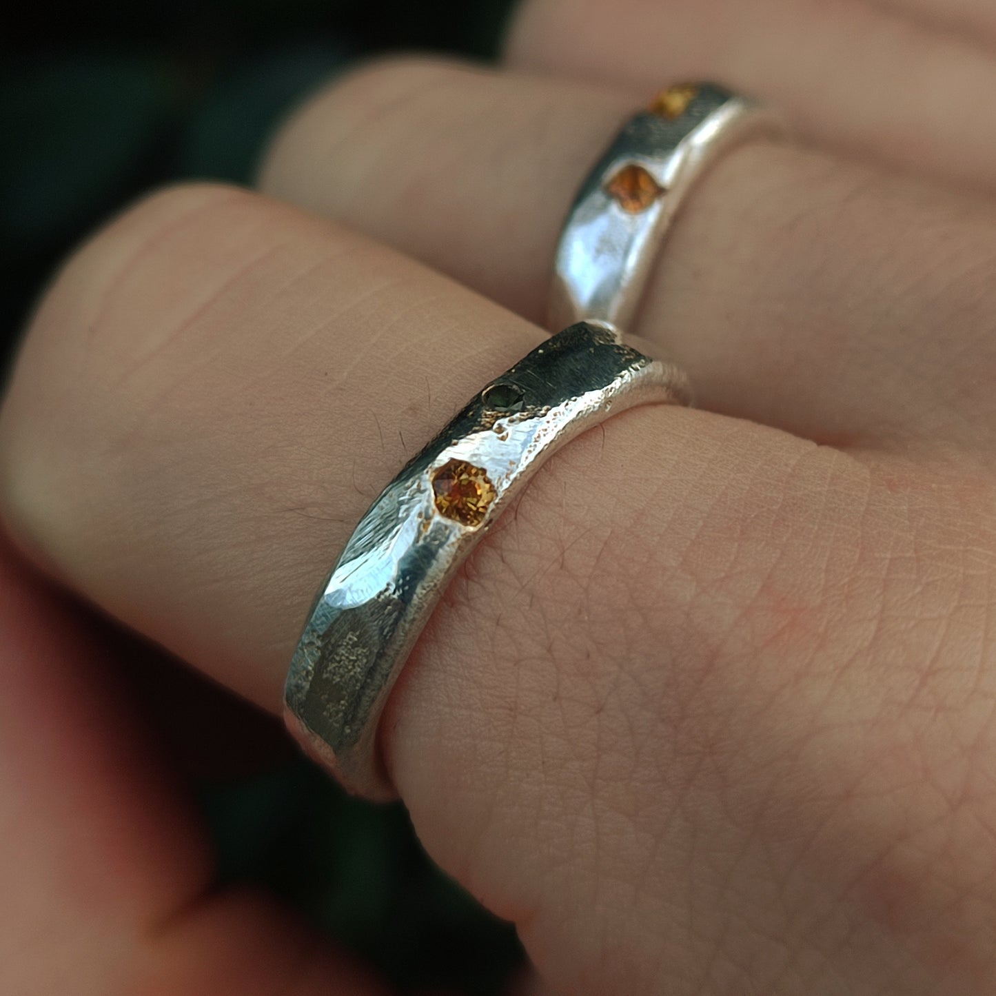 Close-up of two silverhollowjewellery Sand Cast Sapphire Rings, crafted from recycled sterling silver and worn on adjacent fingers.