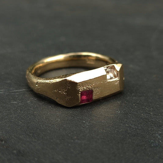 The 9ct Sandcast Sapphire/Ruby Signet by silverhollowjewellery is crafted from recycled gold using sand casting, featuring a textured band and square ruby and white sapphire set side by side on a rectangular bezel.