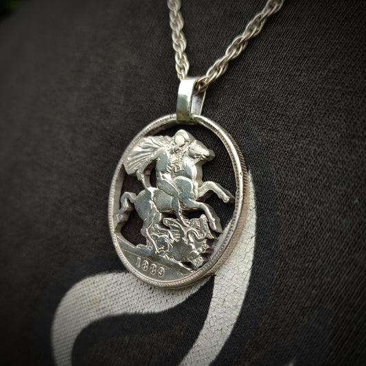 A close-up of the silverhollowjewellery Sterling Silver Crown Coin Pendant 1800s, showcasing its intricate coin design, worn over a dark shirt.