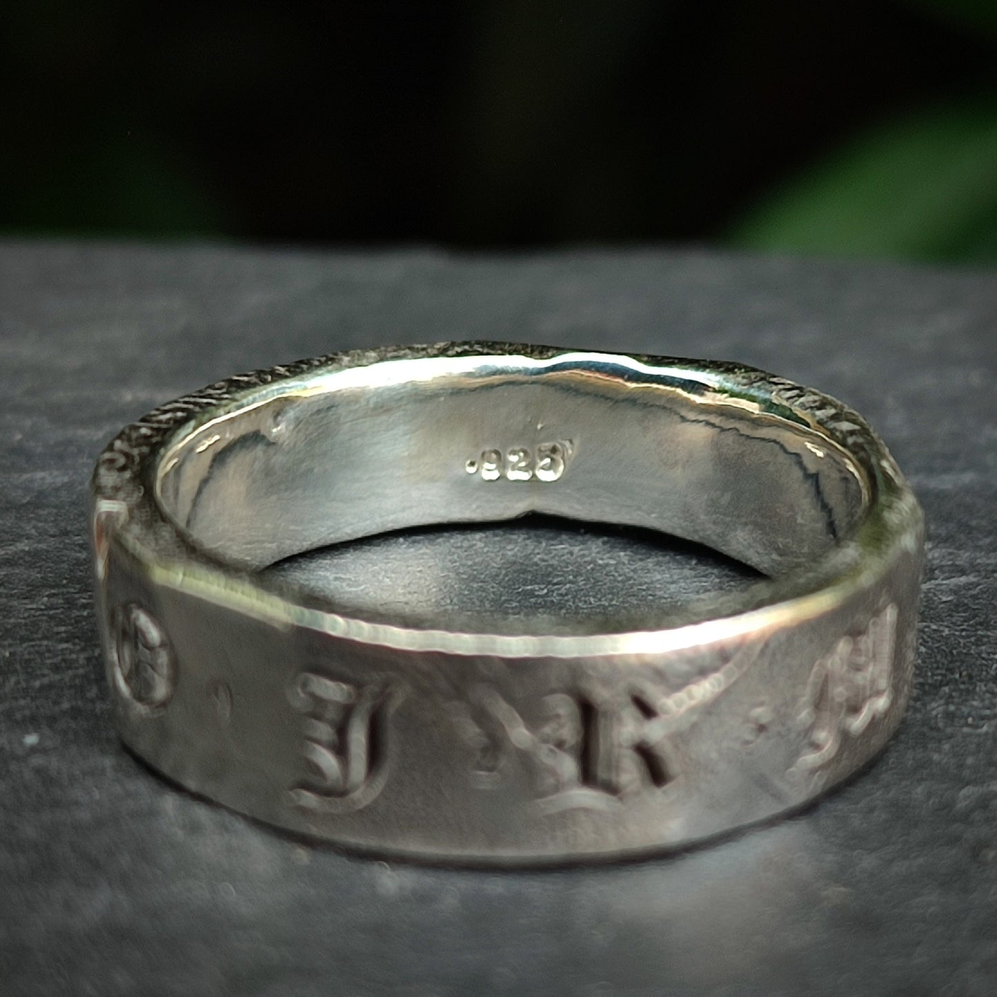 The Custom Distressed Hallmark Ring by silverhollowjewellery is a sterling silver band engraved with "925" inside and features embossed Old English-style letters outside—an elegant, eco-friendly piece.