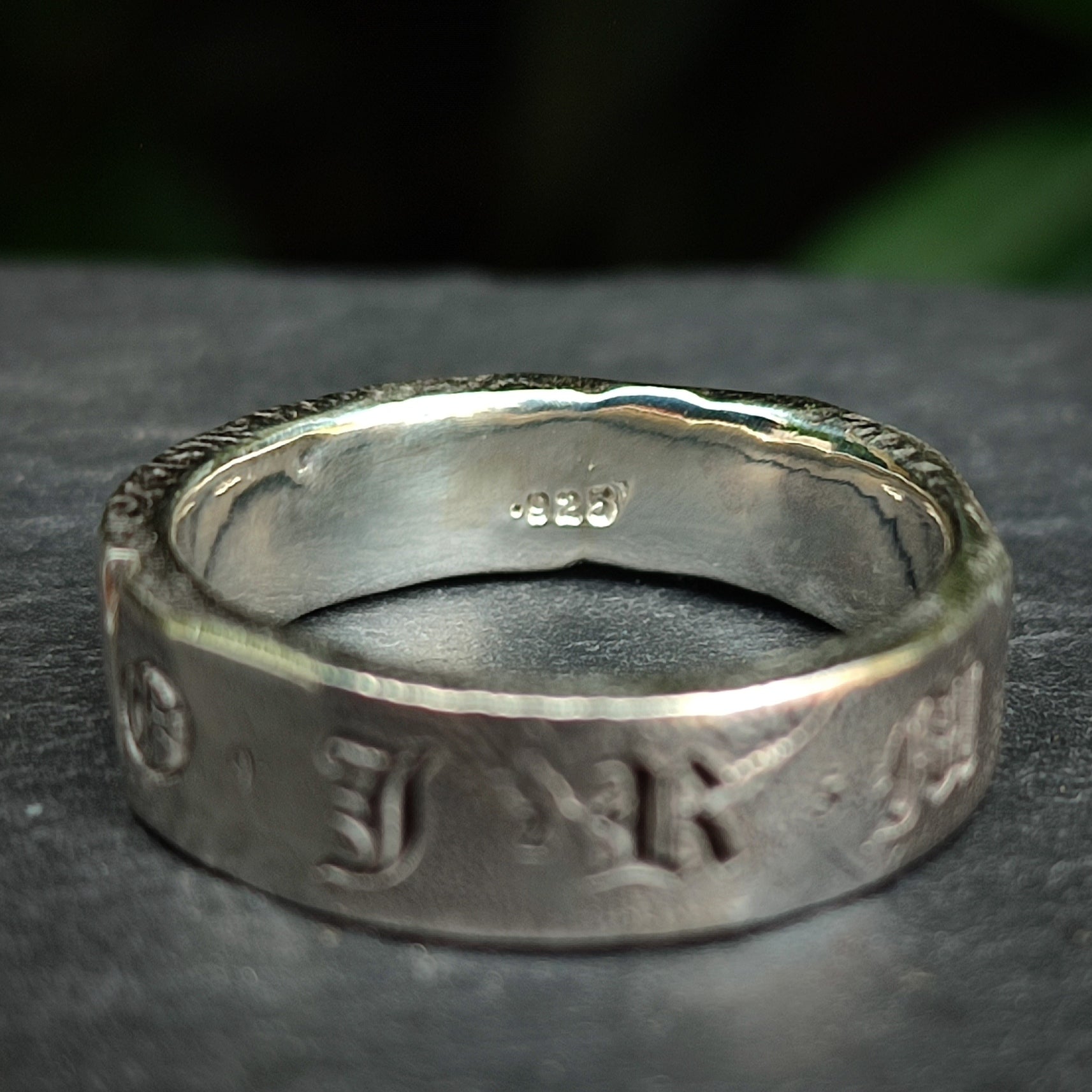The Custom Distressed Hallmark Ring by silverhollowjewellery is a sterling silver band engraved with "925" inside and features embossed Old English-style letters outside—an elegant, eco-friendly piece.