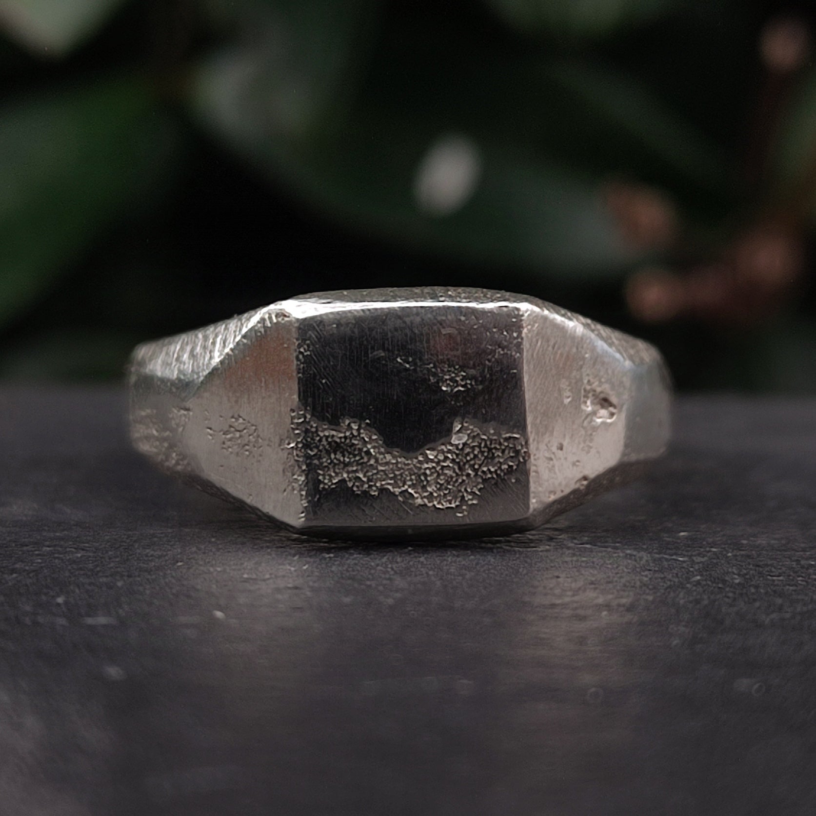 The Raw Square Signet by silverhollowjewellery is a close-up of a recycled 925 sterling silver ring with a geometric rectangular face, showcasing a unique naturally formed texture and worn finish.