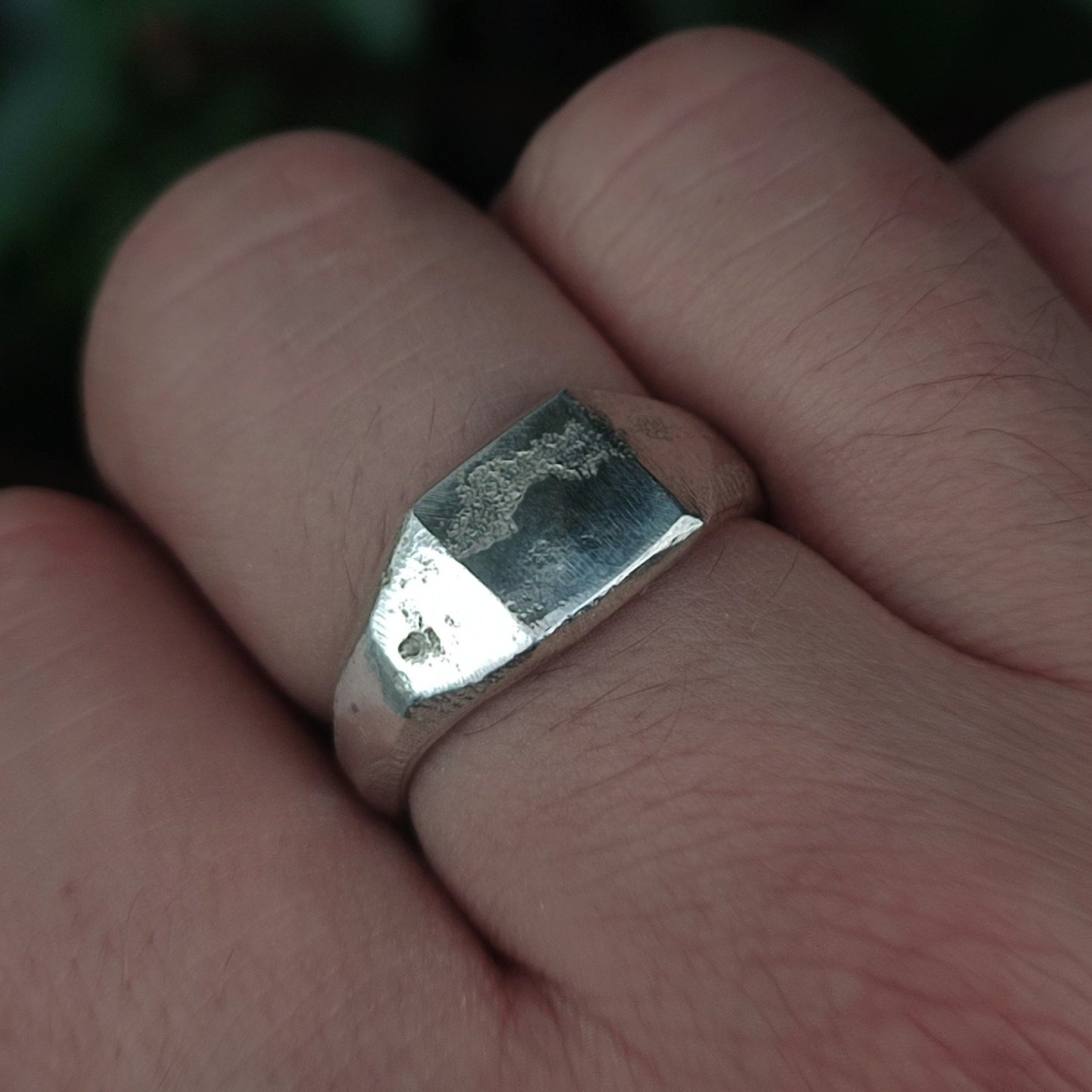 A close-up of a hand wearing the Raw Square Signet by silverhollowjewellery. Its organic texture, worn surface, and flat rectangular face showcase the distinctive character and artisanal craftsmanship of this sterling silver ring.