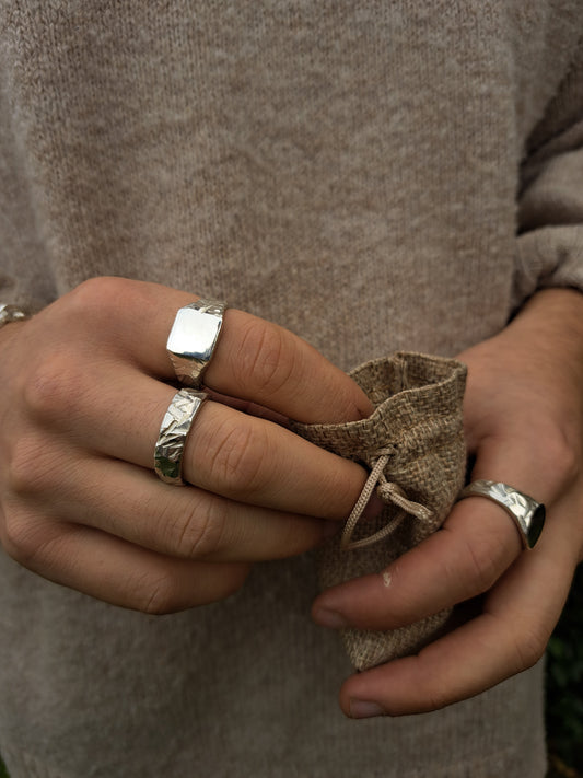 Terraform Collection Rings being worn, whilst holding a bag of silver and gold rings