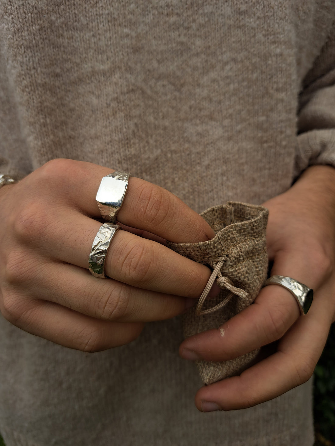 Terraform Collection Rings being worn, whilst holding a bag of silver and gold rings
