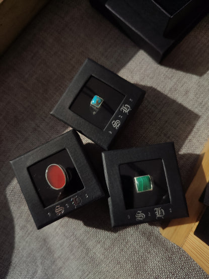 Three different bespoke gemstone rings on display in ring boxes