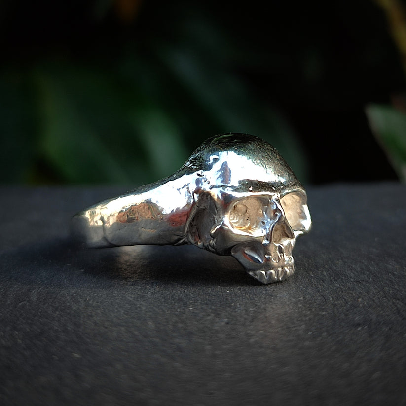 Hand made sterling silver skull ring displayed on a slate slab