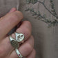 Silver ring with thistle design worn on a finger against a textured fabric background