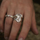Close-up of a hand wearing two silver rings with floral designs on a blurred background