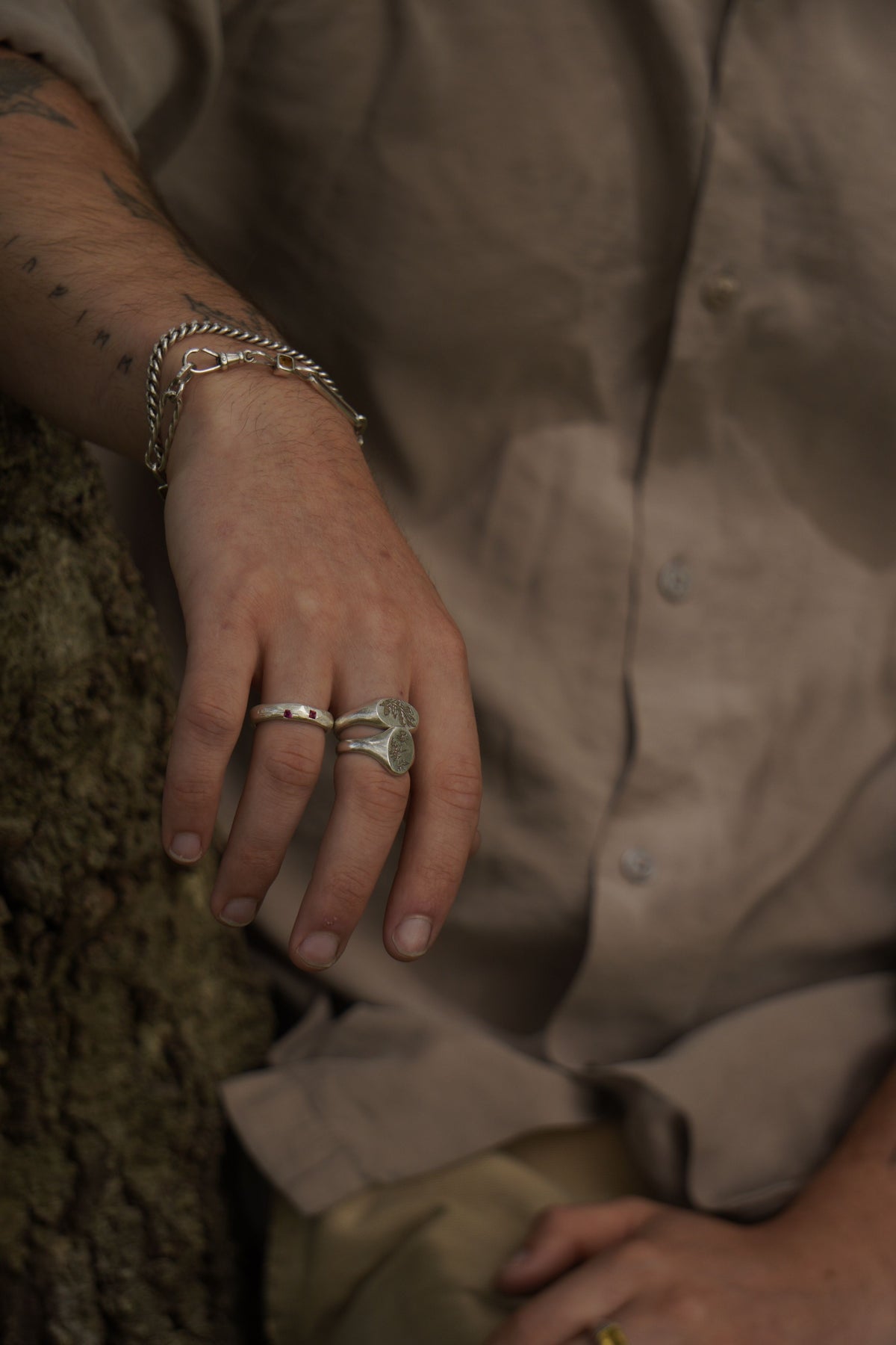 Close-up of a hand wearing three rings with a blurred person in a shirt in the background