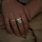 Close-up of hands with multiple rings on a beige fabric background