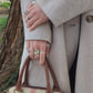Woman wearing spoon rings holding a handbag 