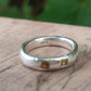 A silver ring band set with two square yellow sapphires, with a .925 stamp on the inside of the ring 