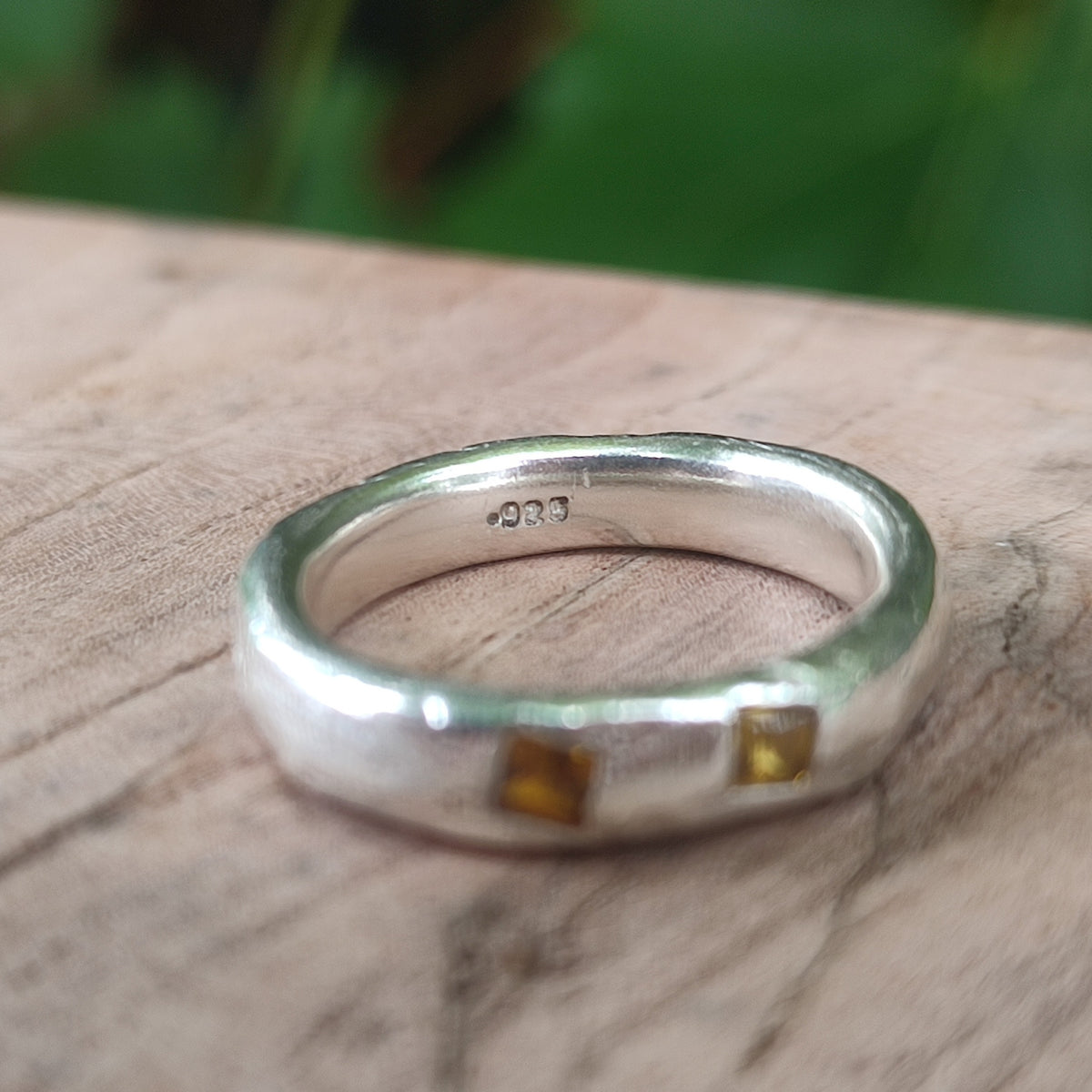 A silver ring band set with two square yellow sapphires, with a .925 stamp on the inside of the ring 