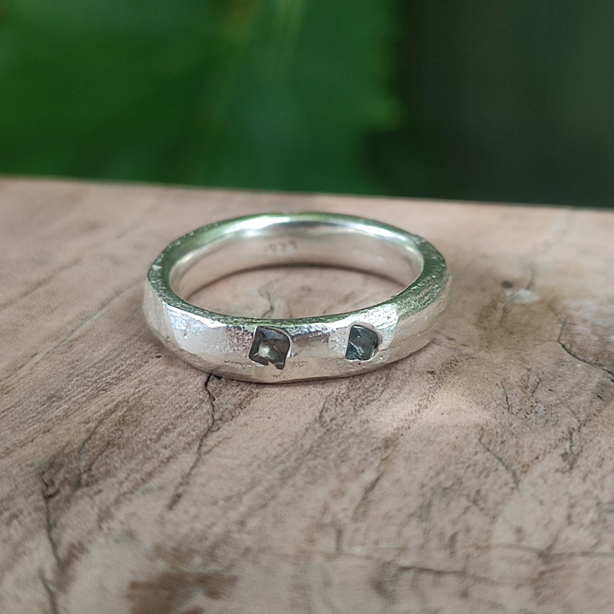 Handcrafted silver teal sapphire ring with a textured sand cast band, viewed from above